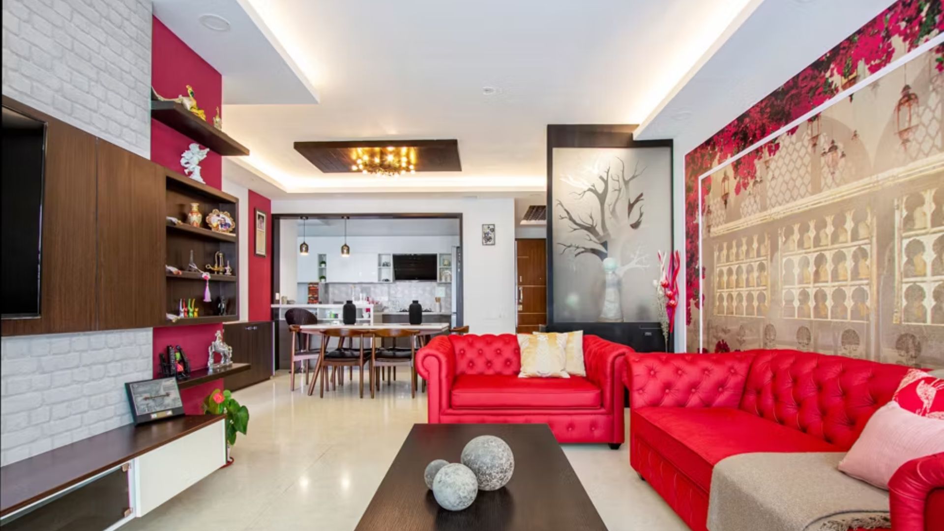 Modern living room with red sofa set and stylish wall décor in a 3BHK flat.